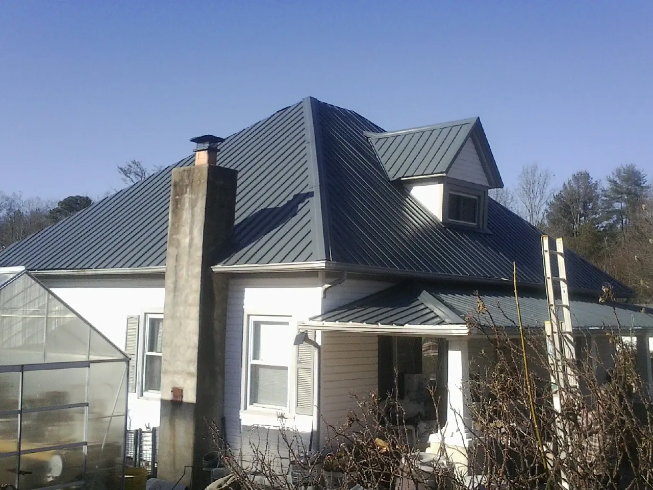 Dark blue standing seam metal roof on a white farmhouse with dormer — Slate & Tile Roof Repair by Roofing Brothers in Astoria
