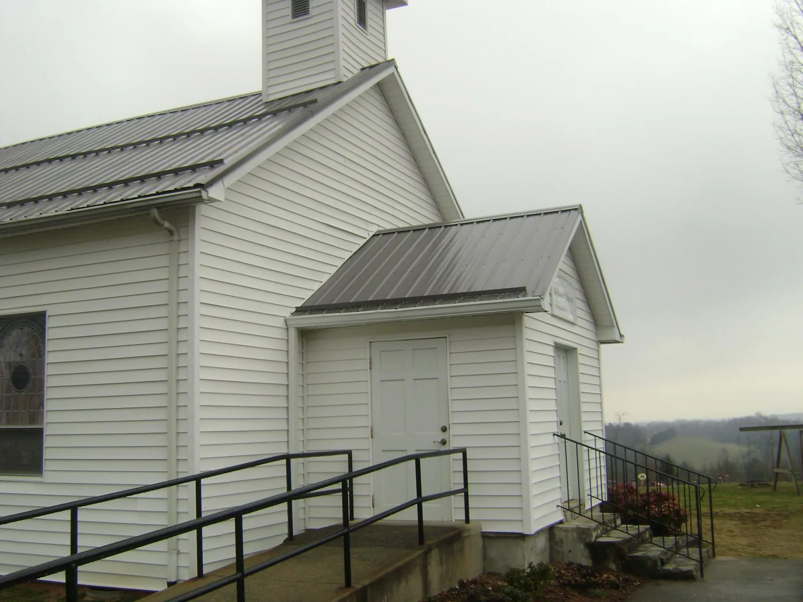 Gray metal roof on a white clapboard church with a steeple in Astoria
