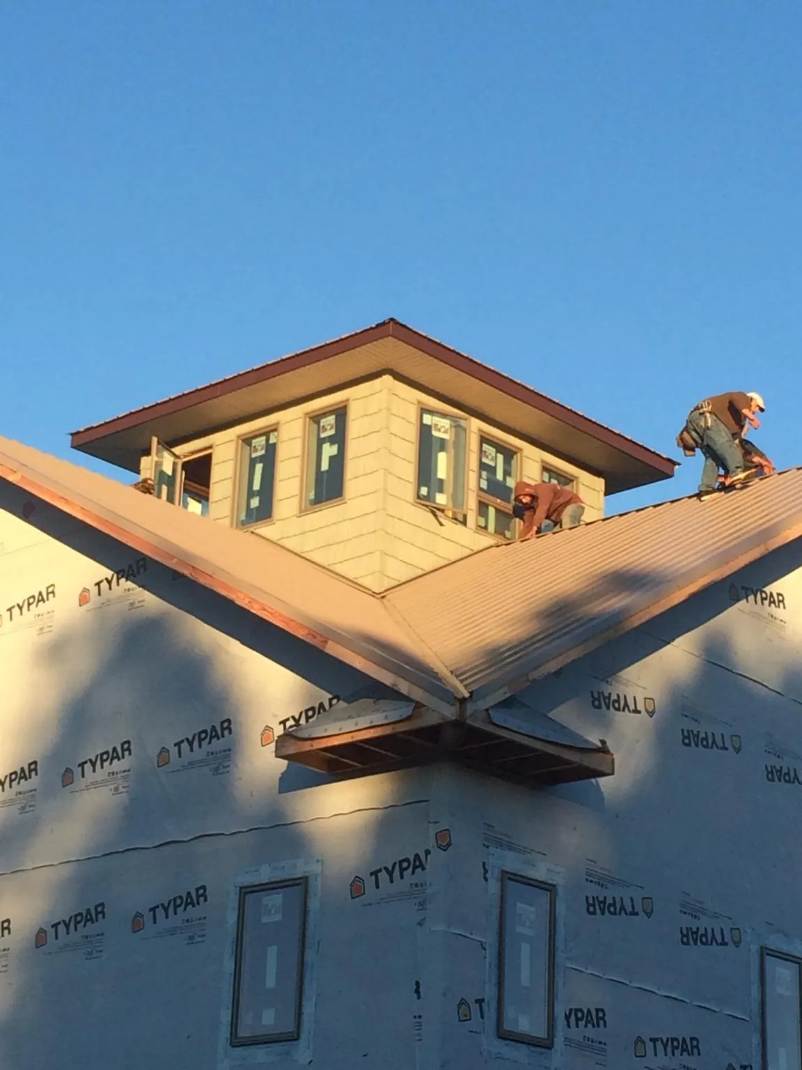 Roofers working around a rooftop cupola on a new metal roof at sunset — Roof Waterproofing in Astoria by Roofing Brothers